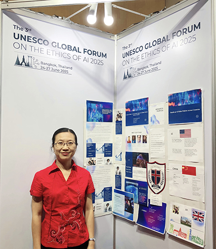 Dr. Chen standing by a white poster highlighting DBU's progams