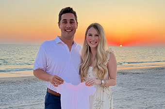 John Austin Earles standing outside with his wife with sunset in the background above the water